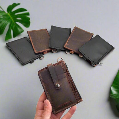 Handmade leather keychain wallet in crazy horse color, featuring a secure snap closure and brass hardware. Hand holding the leather keychain wallet to show its compact size and portability.